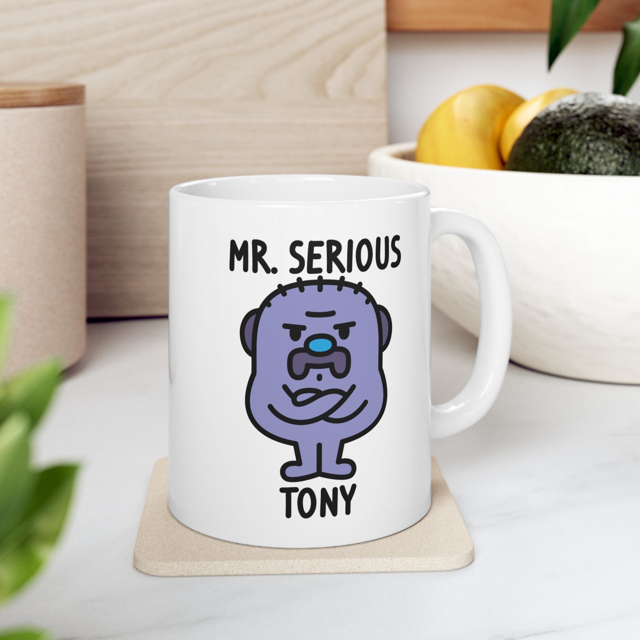 White mug with a cartoon character and text 'Mr. Serious' on a wooden coaster.