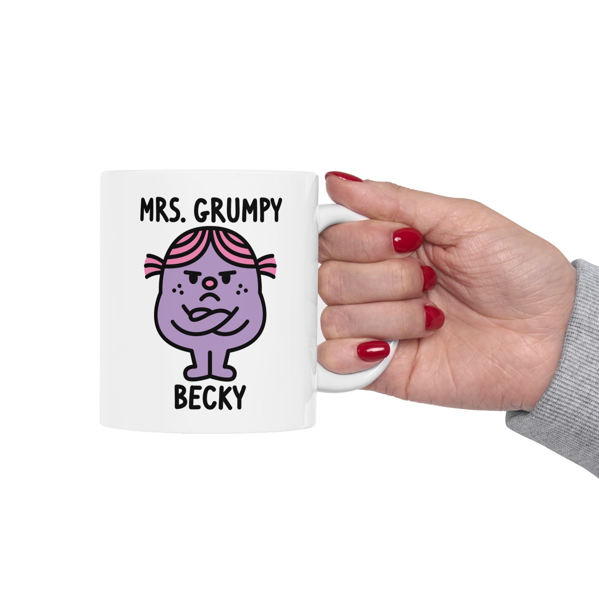 Mug with cartoon character 'Mrs. Grumpy' held by a hand with red nail polish on a white background